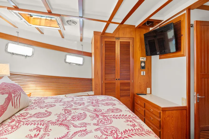 Cozy bedroom in 1996 Kadey-Krogen 48 Whaleback yacht with wood accents and floral bedding.
