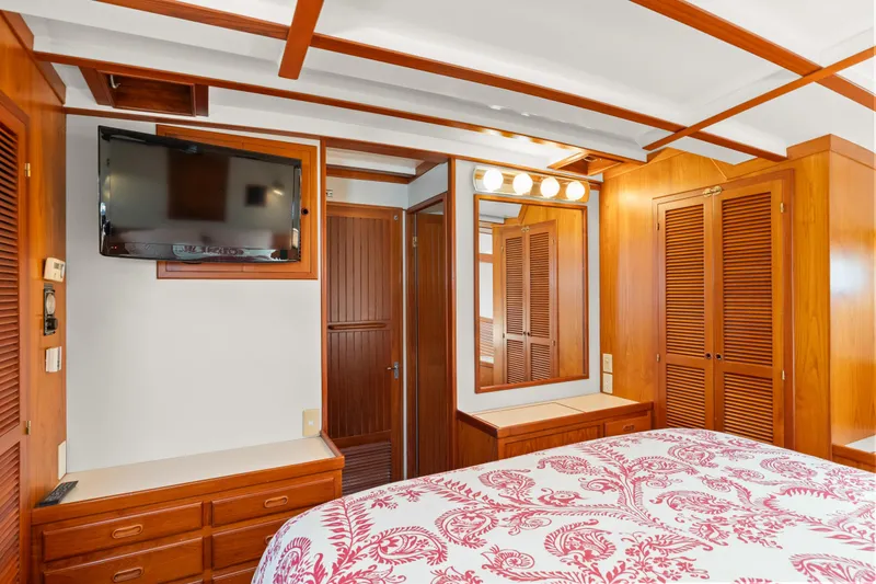 Luxurious 1996 Kadey-Krogen 48 Whaleback bedroom with wood paneling and floral bedding.