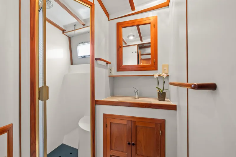 Bathroom interior of 1996 Kadey-Krogen 48 Whaleback yacht with wooden accents and mirror.