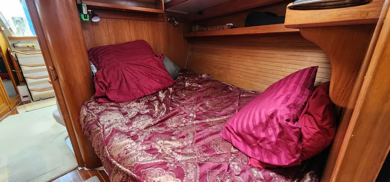 Cozy cabin interior of 1995 Catalina 42 MkII with red bedding and wooden accents.