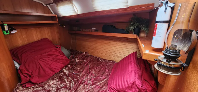 Cozy cabin interior of a 1995 Catalina 42 MkII sailboat with red bedding and wooden finish.