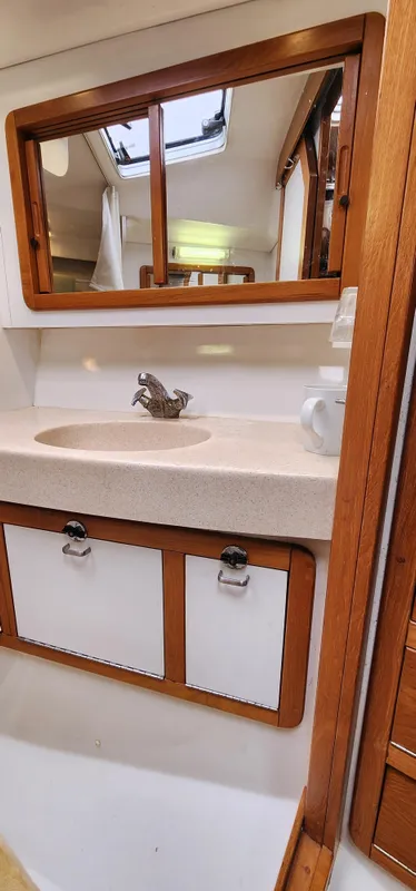 Catalina 42 MkII 1995 yacht bathroom with sink, mirror, and wooden cabinetry.