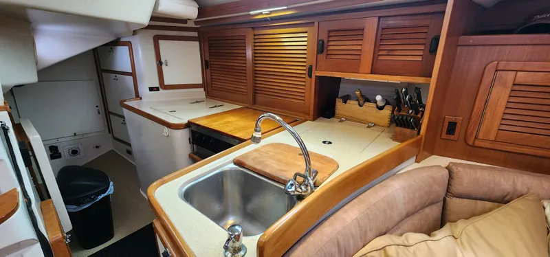 Interior of 1995 Catalina 42 MkII yacht, featuring a compact kitchen with wooden cabinetry.