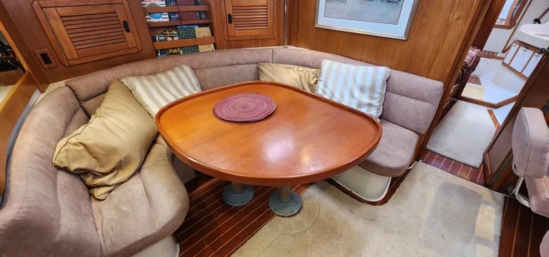 Cozy dining area in a 1995 Catalina 42 MkII sailboat with cushioned seating and wooden table.