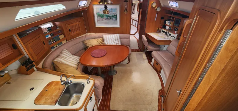 Interior of a 1995 Catalina 42 MkII sailboat with cozy seating and wooden finishes.