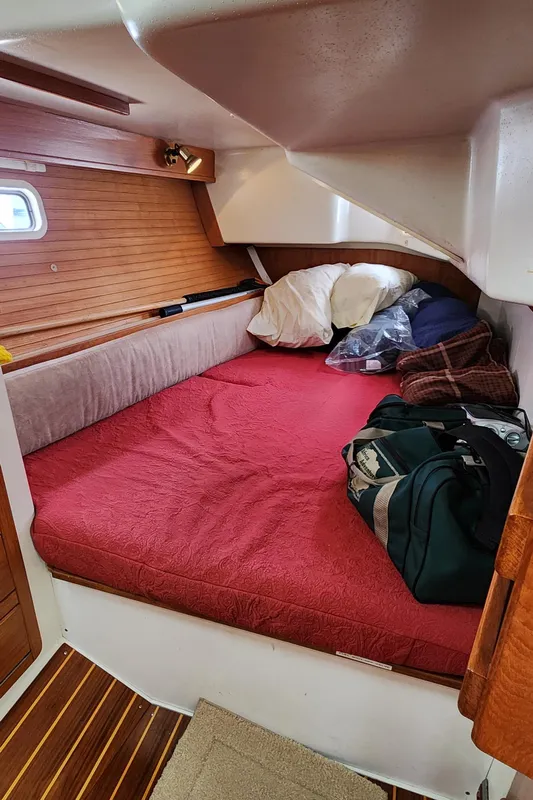 Cozy cabin interior of a 1995 Catalina 42 MkII sailboat with red bedding and wooden accents.