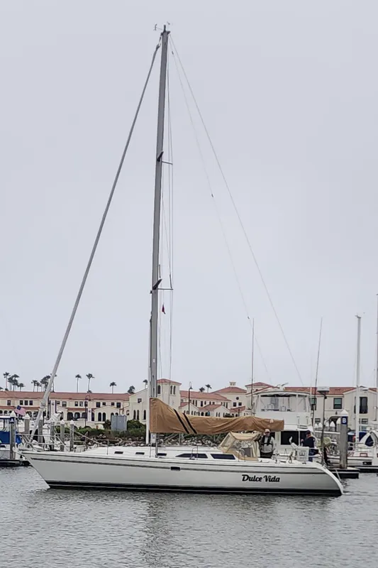 1995 Catalina 42 MkII sailboat docked in marina, overcast sky.
