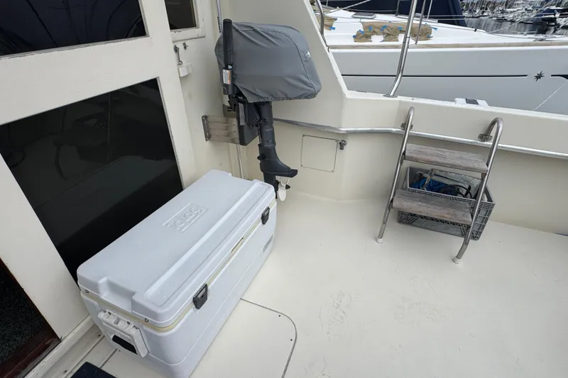 1983 Hatteras 36 Convertible boat deck with cooler, ladder, and covered motor.