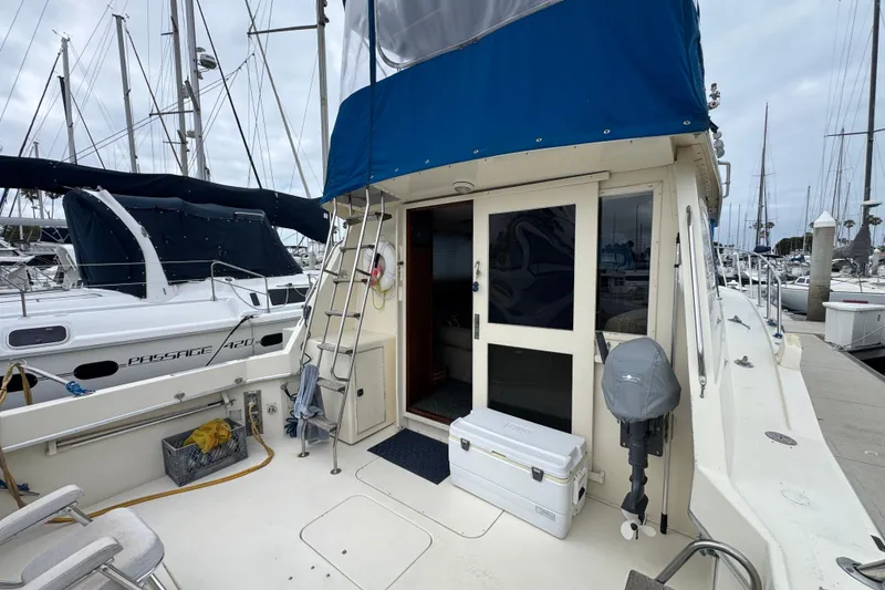 1983 Hatteras 36 Convertible yacht docked at marina, featuring blue canopy and spacious deck.