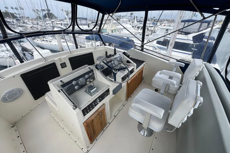 Cockpit of 1983 Hatteras 36 Convertible yacht with helm and seating, docked at marina.