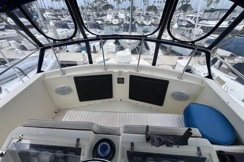 Cockpit view of 1983 Hatteras 36 Convertible yacht in marina, showcasing helm and seating area.