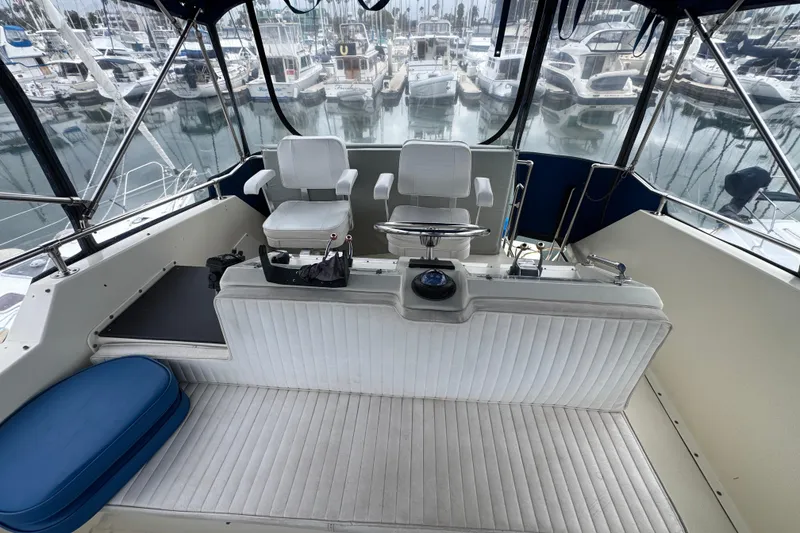 1983 Hatteras 36 Convertible yacht interior with helm and seating, docked at marina.