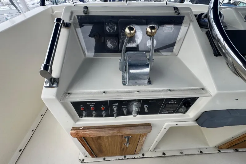 Control panel of a 1983 Hatteras 36 Convertible boat with dual throttle levers.