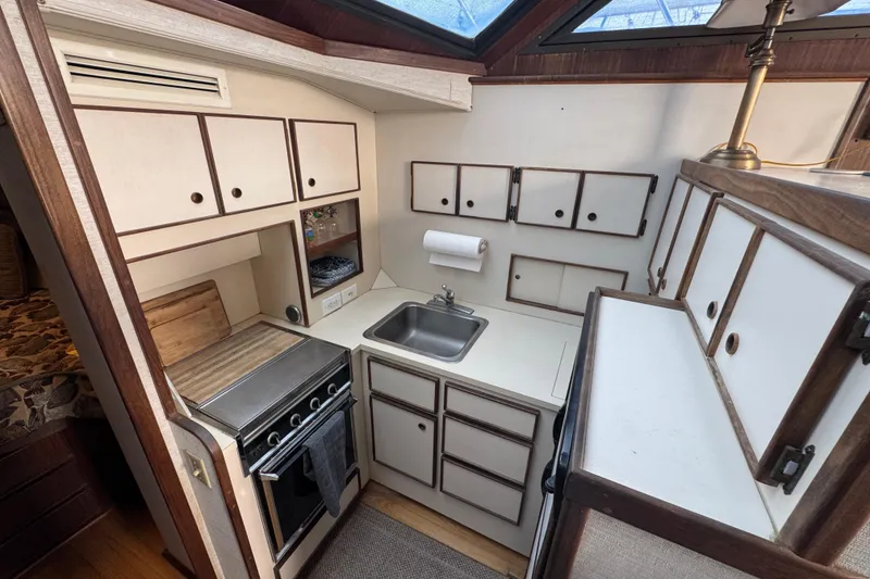 Compact kitchen in 1983 Hatteras 36 Convertible yacht with stove, sink, and cabinets.
