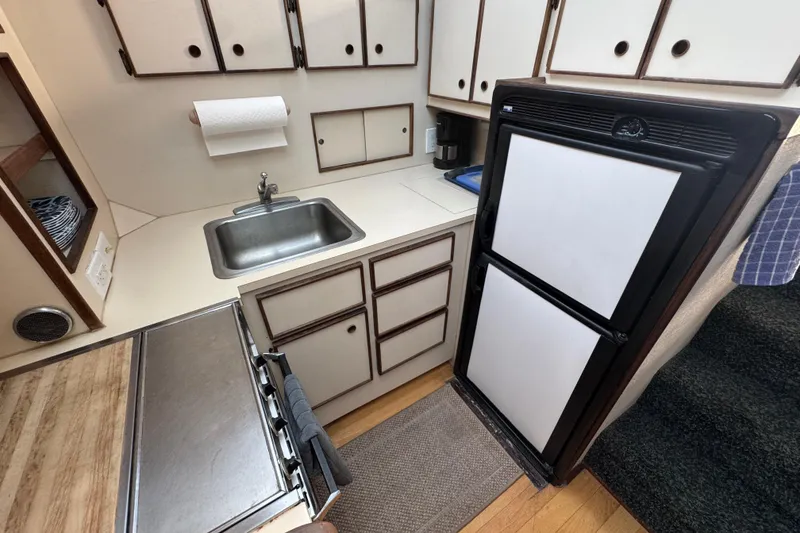 Compact kitchen in 1983 Hatteras 36 Convertible boat with sink, stove, and fridge.