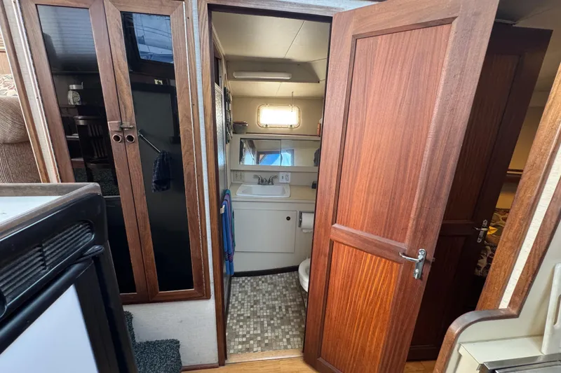 1983 Hatteras 36 Convertible yacht interior with wooden cabinetry and compact bathroom.