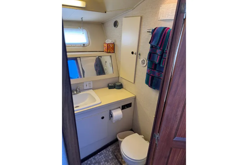 1983 Hatteras 36 Convertible yacht bathroom with sink, mirror, and colorful towels.
