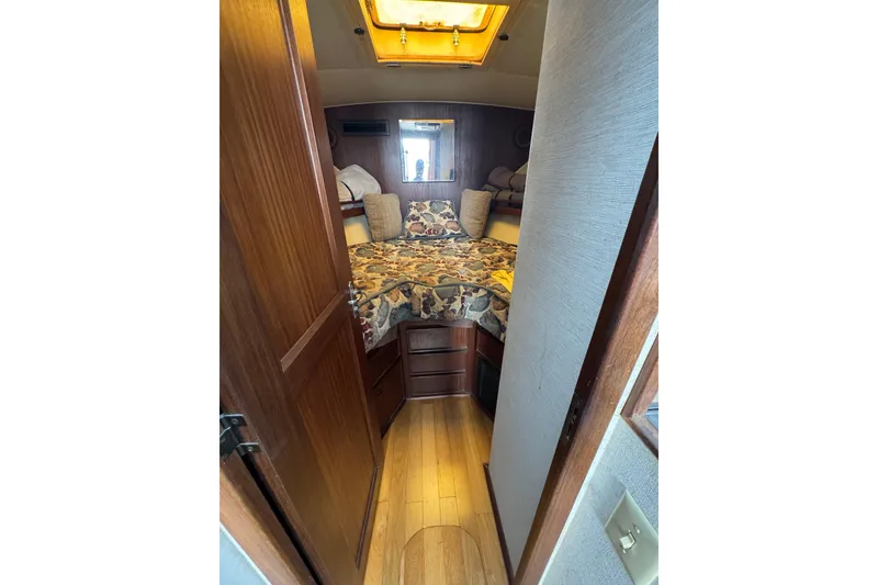 Interior cabin of 1983 Hatteras 36 Convertible yacht with cozy bed and wooden accents.