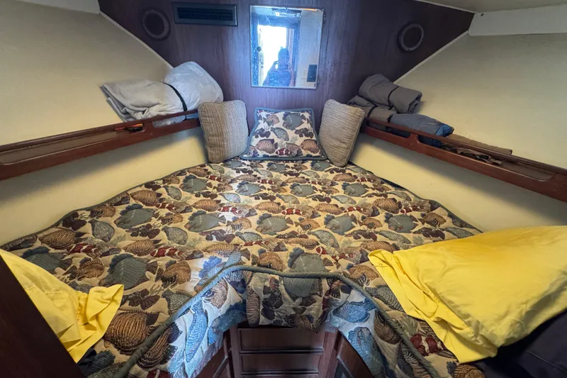 Cozy cabin interior of 1983 Hatteras 36 Convertible with patterned bedding and pillows.