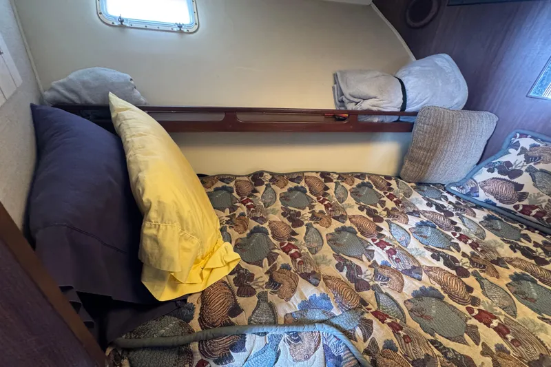 Cozy cabin interior of 1983 Hatteras 36 Convertible with patterned bedding and pillows.