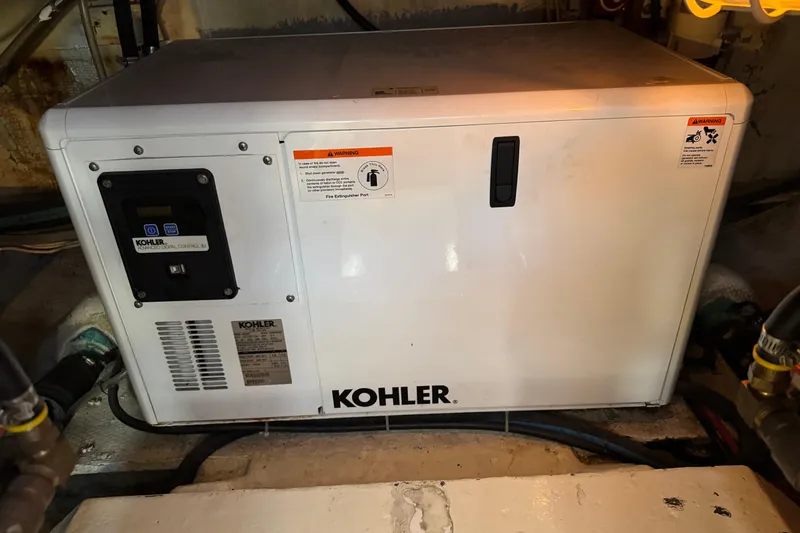 Kohler generator in 1983 Hatteras 36 Convertible engine room, displaying control panel and warning labels.