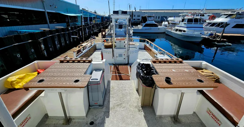 1958 Ditmar & Donaldson sport boat docked, featuring spacious seating and wooden tables.