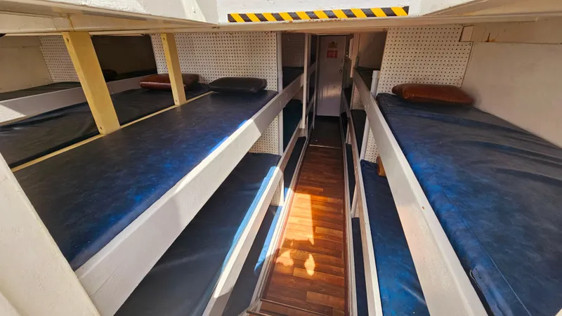 1958 Ditmar & Donaldson sport boat interior with multiple bunk beds and wooden flooring.