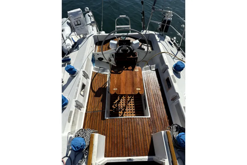 Cockpit of 1985 Beneteau First 38 sailboat with wooden deck and steering wheel.