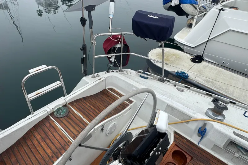 Cockpit of a 1985 Beneteau First 38 sailboat with wooden flooring and steering wheel.