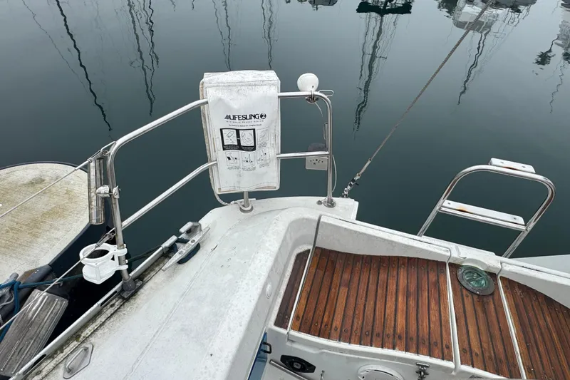 Stern view of 1985 Beneteau First 38 sailboat with lifesaving equipment and wooden deck.