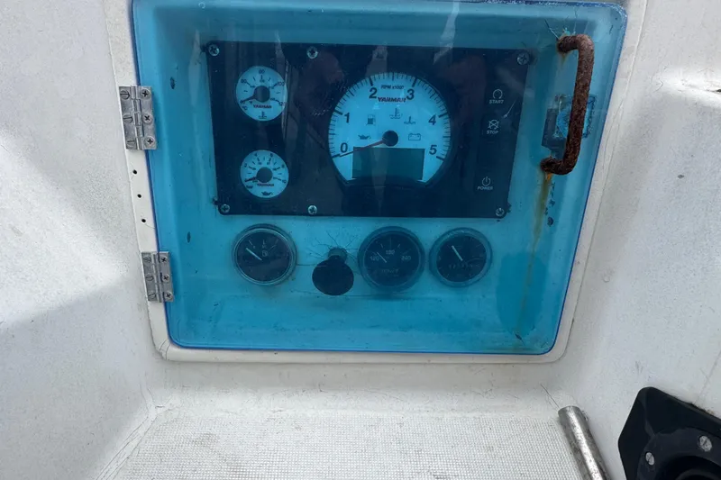 Control panel of a 1985 Beneteau First 38 sailboat with gauges and rusted handle.