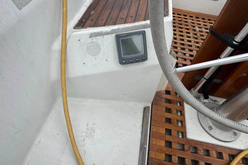 Cockpit of 1985 Beneteau First 38 sailboat with wooden flooring and navigation display.