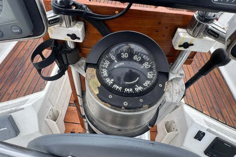 Compass on 1985 Beneteau First 38 sailboat, wooden deck background.