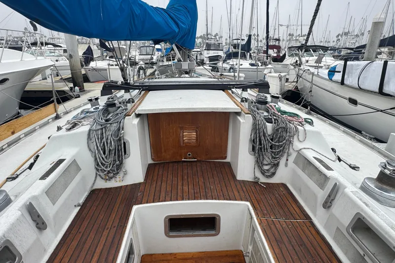 1985 Beneteau First 38 sailboat cockpit with ropes and wooden deck in marina.