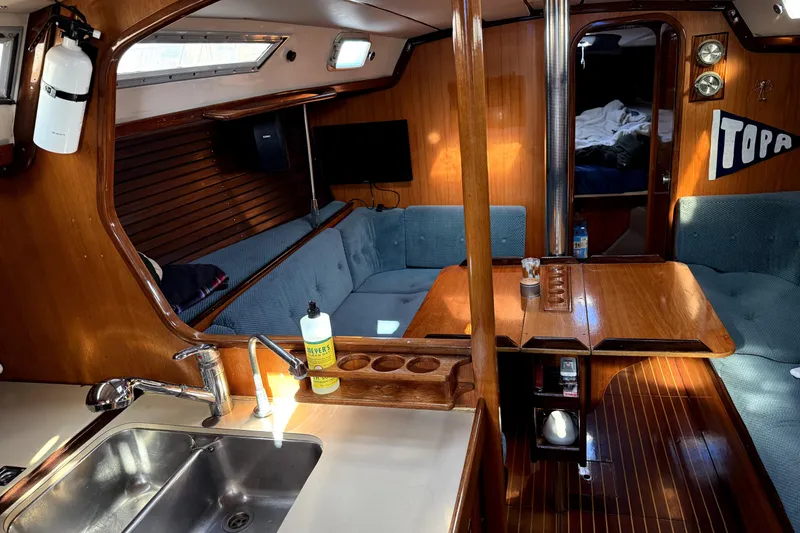 Interior of 1985 Beneteau First 38 sailboat with wood finish and cozy seating area.