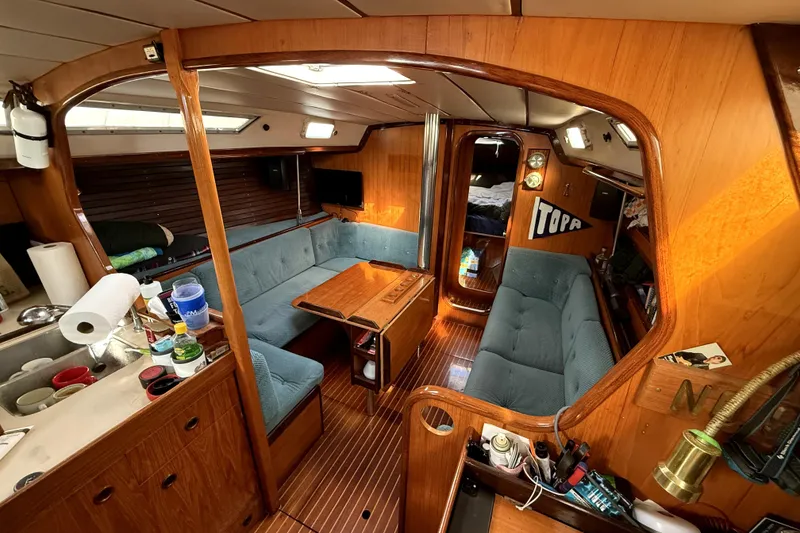 Interior of 1985 Beneteau First 38 sailboat with wooden finish and cozy seating area.