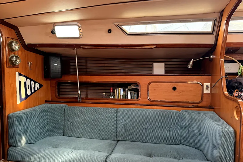 Interior of 1985 Beneteau First 38 sailboat with blue sofa and wooden cabinetry.