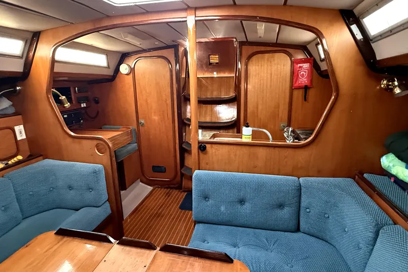 Interior of 1985 Beneteau First 38 sailboat with wood paneling and blue seating.
