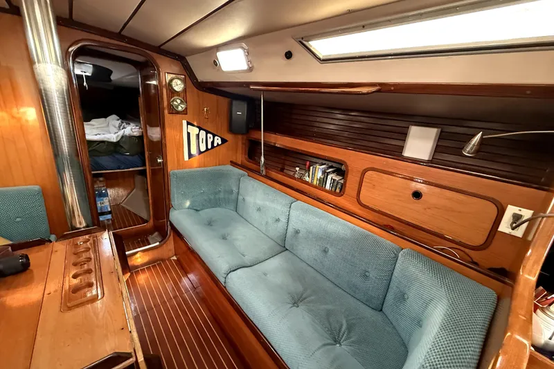 Interior of 1985 Beneteau First 38 sailboat with cozy seating and wooden finishes.