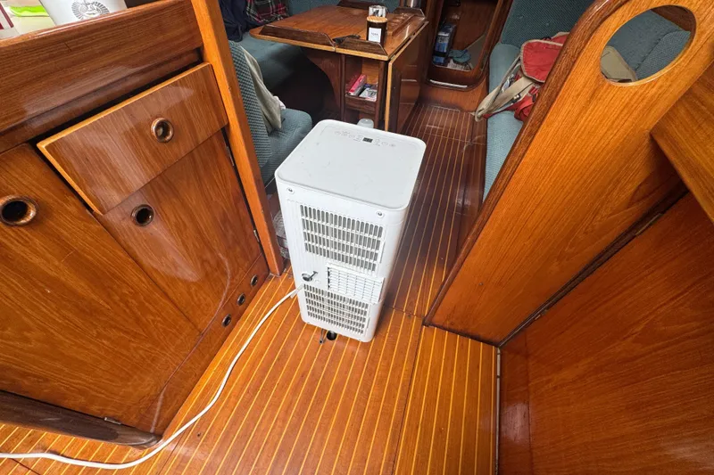 Interior of 1985 Beneteau First 38 sailboat with wooden flooring and a white appliance.