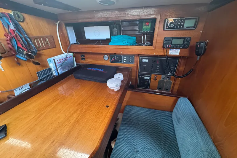 Navigation station inside a 1985 Beneteau First 38 sailboat, featuring control panels and seating.