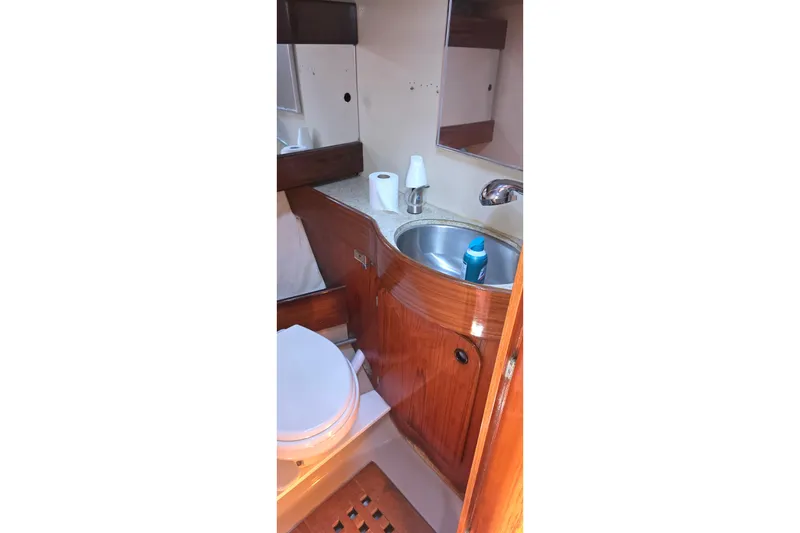 1985 Beneteau First 38 yacht bathroom with wooden cabinetry and stainless steel sink.