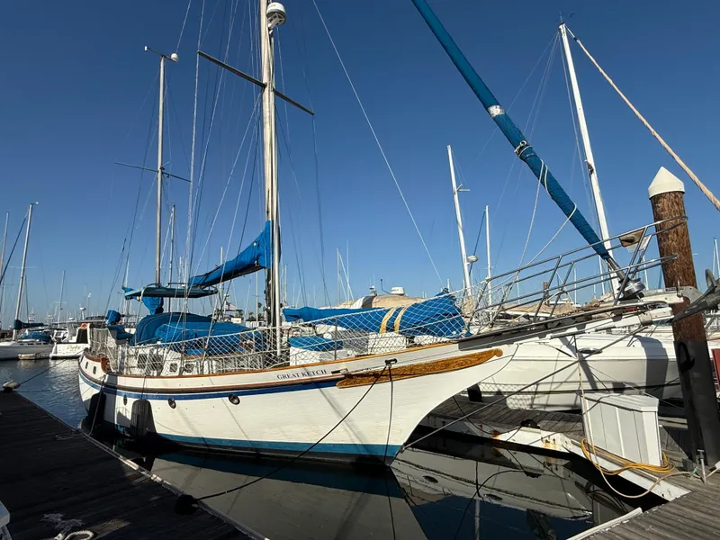 Sailboat Vagabond 47, 1986 model, docked at marina under clear blue sky.