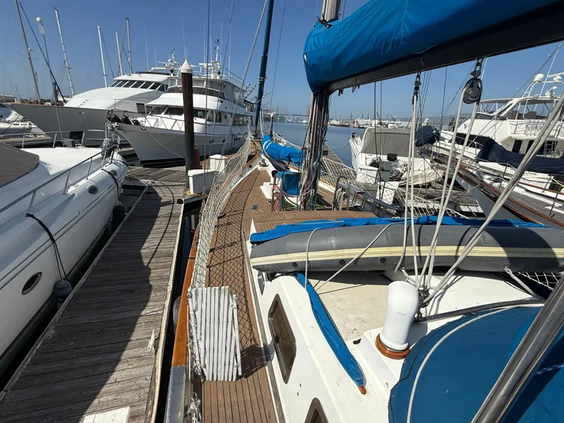 Sailboat Vagabond 47, 1986 model, docked among yachts in a marina.