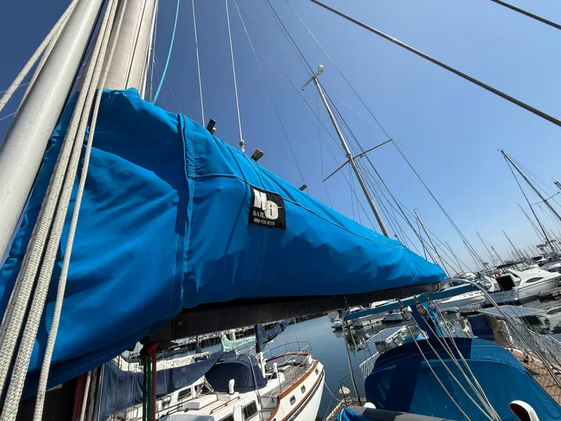 Sailboat with blue cover in marina, Vagabond 47, 1986 model, clear sky background.