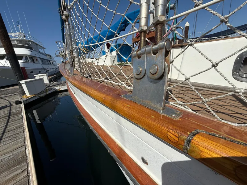 Close-up of 1986 Vagabond 47 sailboat deck with wooden railing and metal fittings.