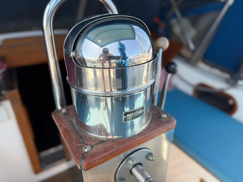 Chrome compass on 1986 Vagabond 47 sailboat, reflecting surroundings.