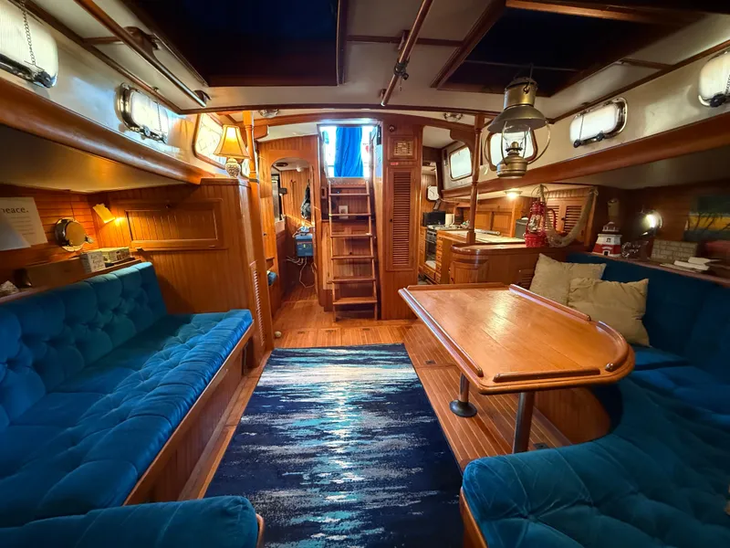 Luxurious 1986 Vagabond 47 yacht interior with blue seating, wooden table, and nautical decor.