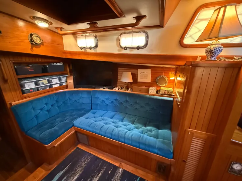 Cozy interior of 1986 Vagabond 47 yacht with blue cushioned seating and wooden accents.
