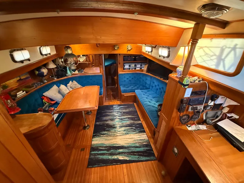 Interior of 1986 Vagabond 47 sailboat with wooden furnishings and blue seating.